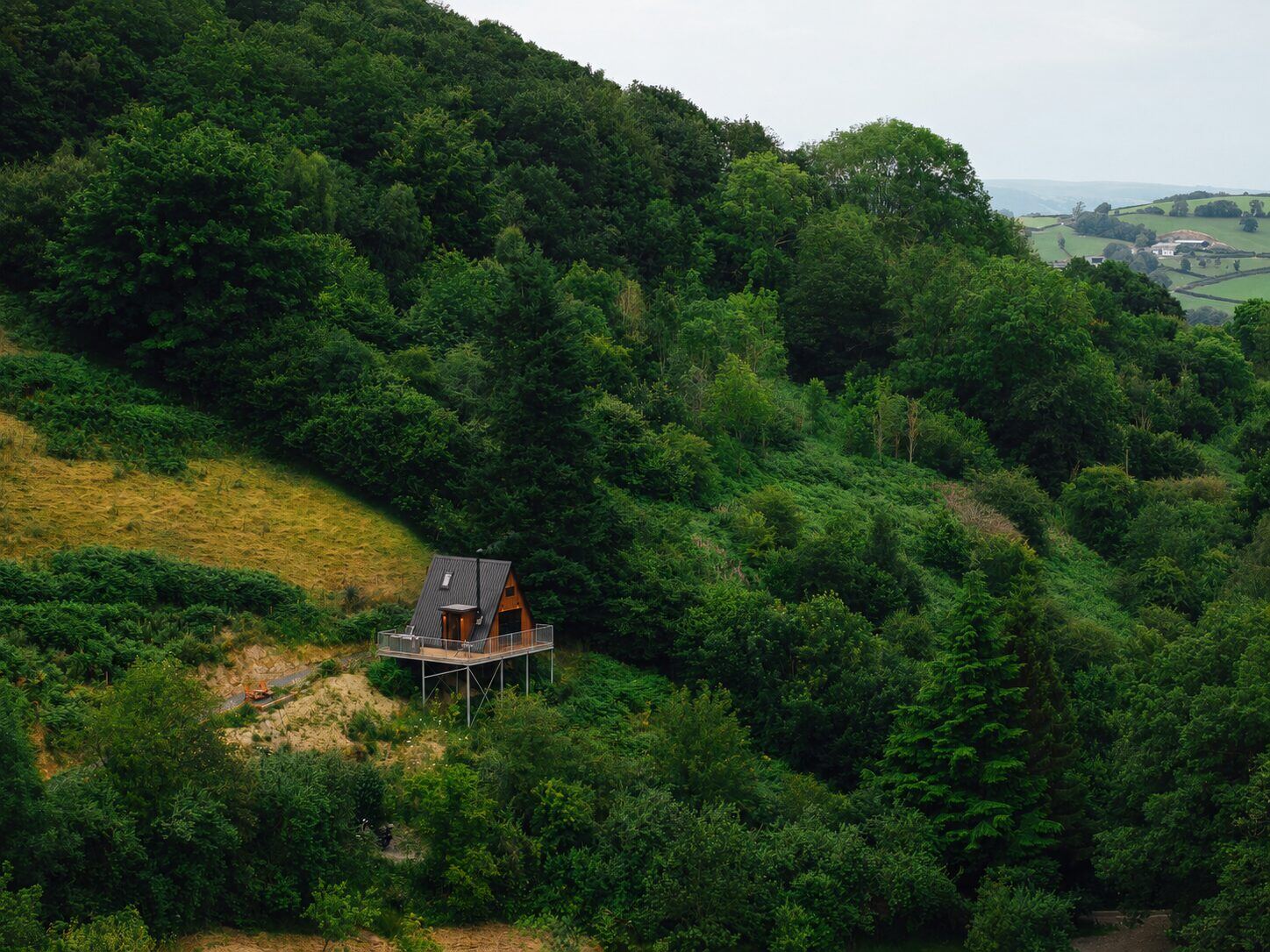 The Perch, a black A-frame cabin with hot tub, nestled in a green Welsh valley above Llanidloes